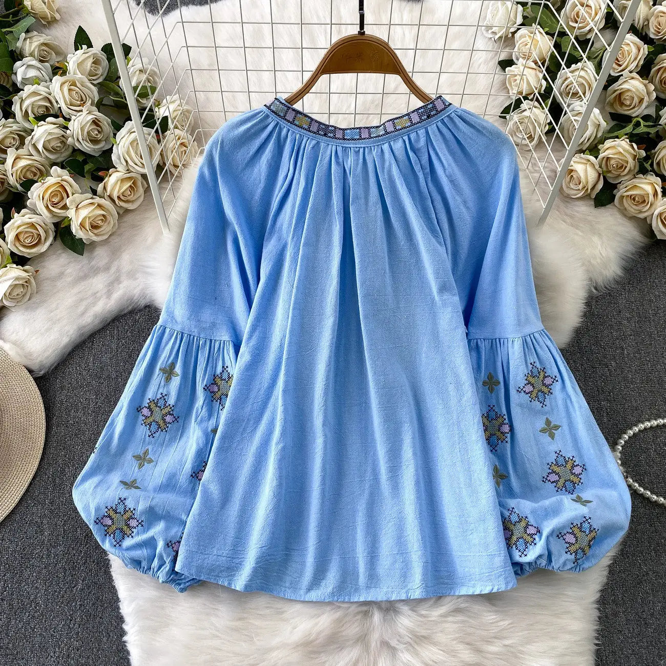 Light blue embroidered lantern sleeve tie neck blouse with puff sleeves and a patterned neckline.