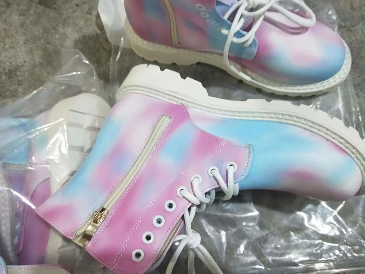Pastellfarbene rosa- und blau-gebatikte Combat-Boots mit klobiger weißer Sohle, mit weißen Schnürsenkeln und einem goldenen Reißverschluss.