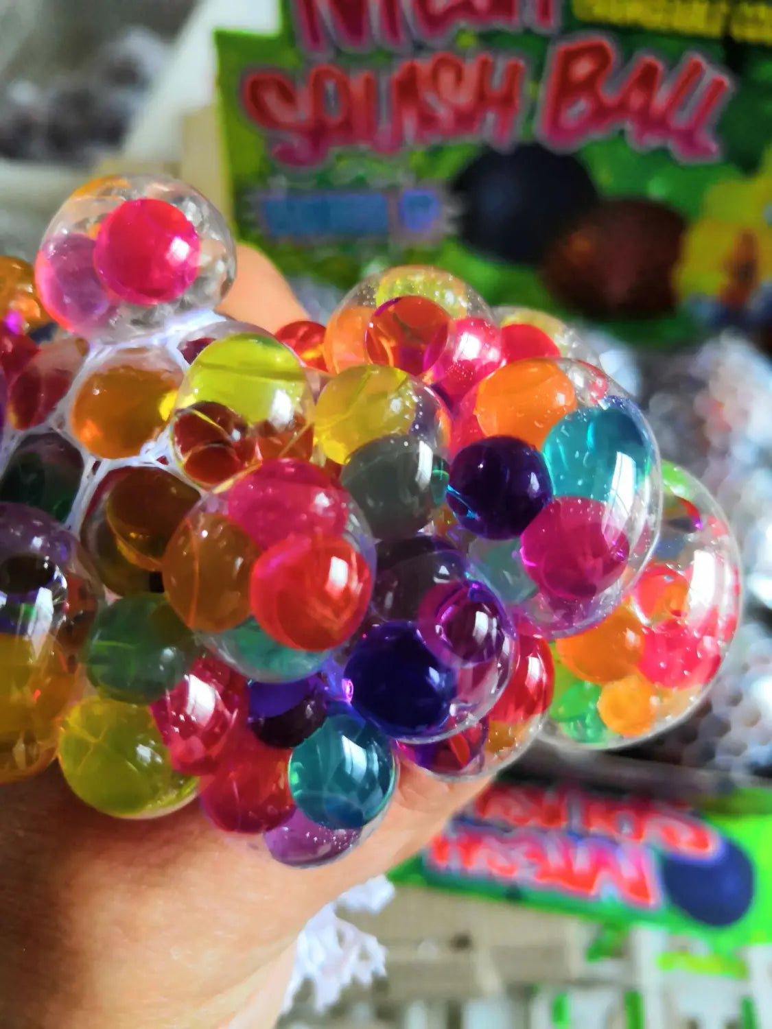 A colorful translucent gel filled led mesh stress ball glowing grape squeeze toy featuring a mesh structure with vibrant spherical beads in assorted hues.