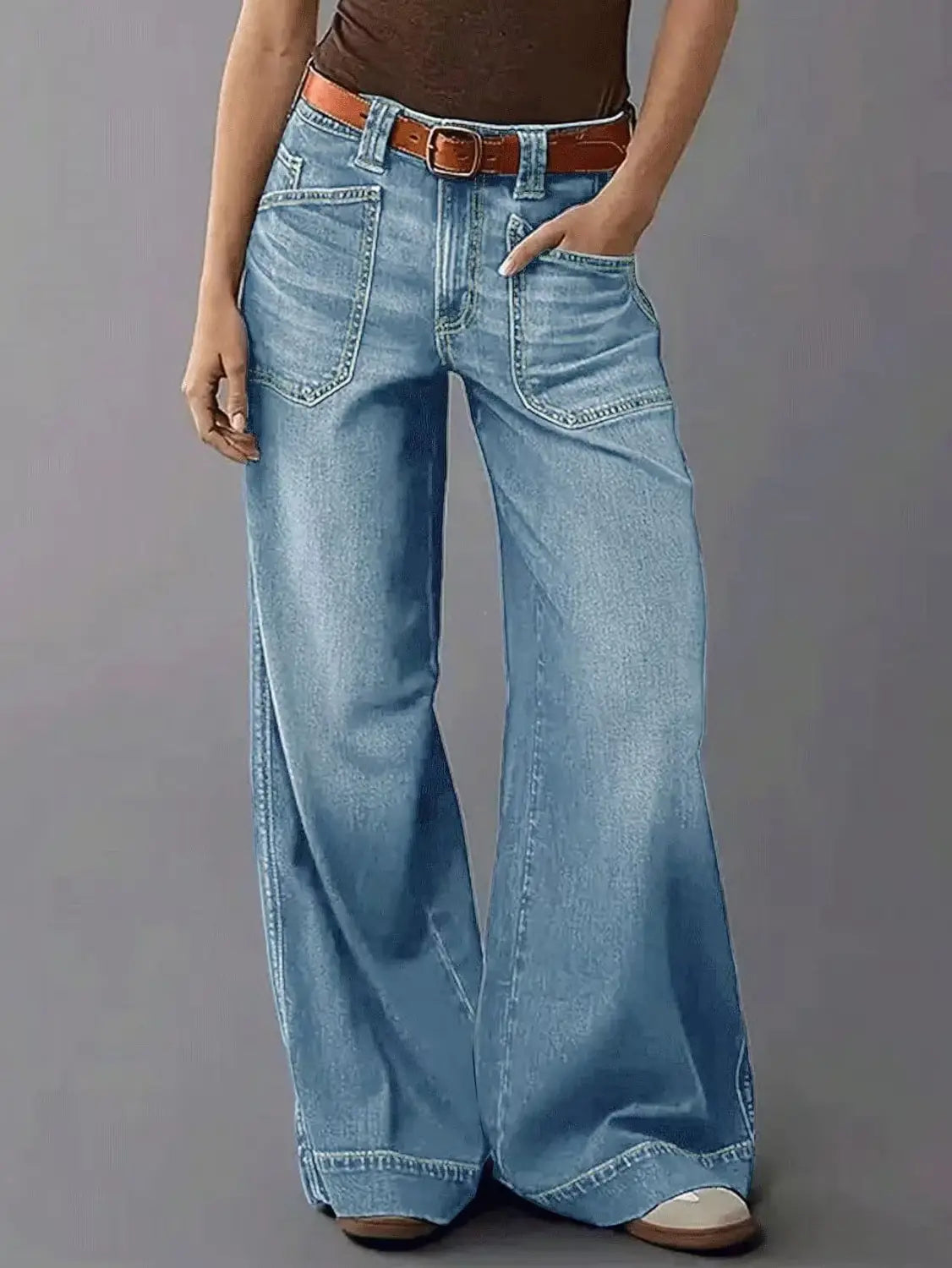Wide leg light-wash denim pants with flare design and brown leather belt shown from the front.