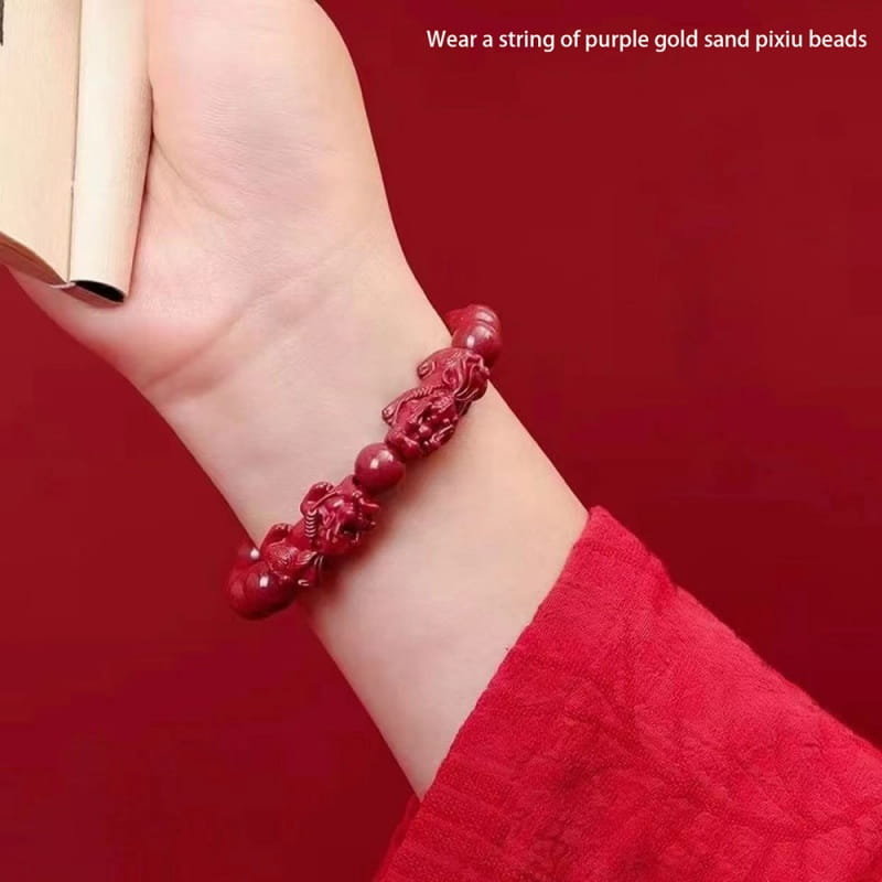 A vibrant red hand carved purple gold cinnabar double pixiu bracelet featuring intricately carved sandalwood pixiu charms and smooth round beads worn on a wrist.