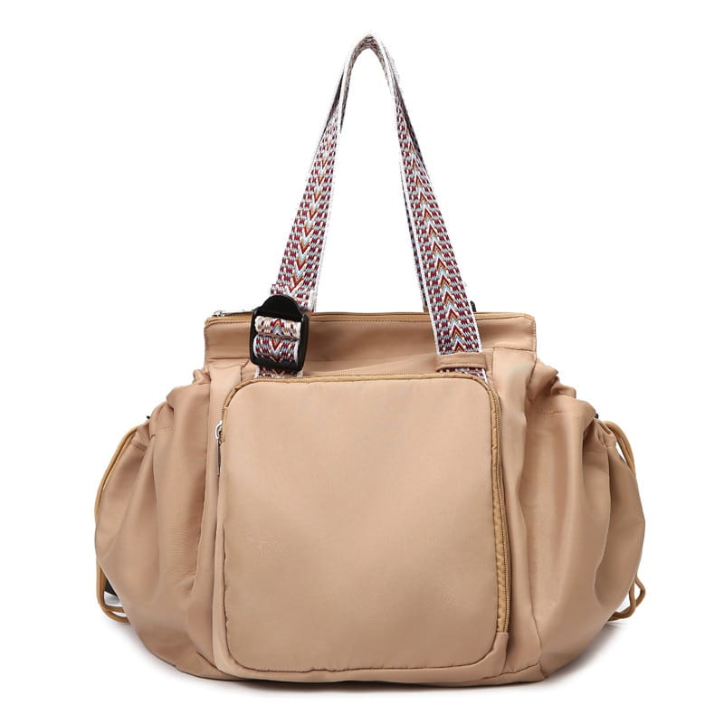 Beige waterproof nylon multifunctional tote and backpack with patterned shoulder straps and a front zippered pocket.