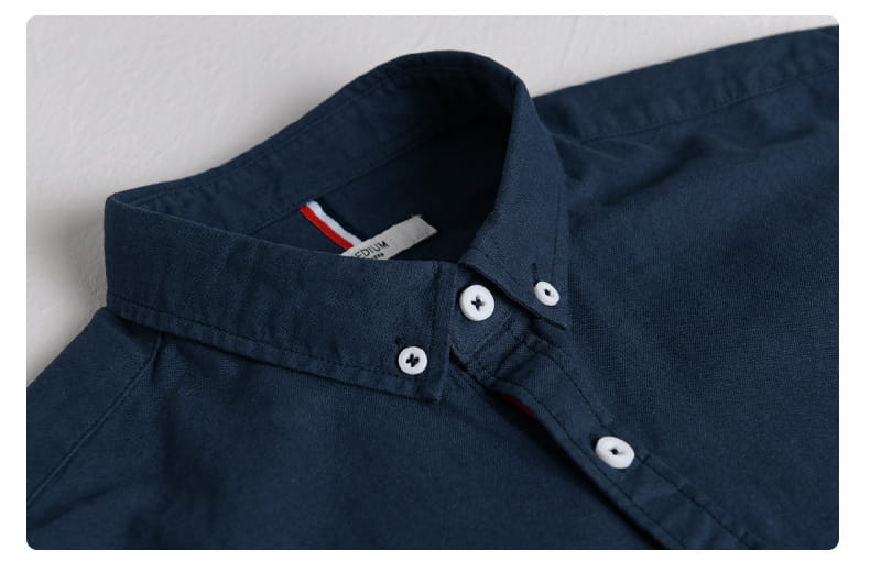 Herren-British-Style-gestreiftes Oxford-Baumwollhemd mit langem Arm in dunkelblau mit weißen Knöpfen und einem rot-weißen und blau-gestreiften Markenanhänger.