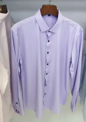 Ein frisches, lavendelfarbenes Herrenhemd mit langem Ärmel, Slim Fit, mit klassischem Kragen und Knopfverschlussfront, auf einem hölzernen Kleiderbügel hängend.