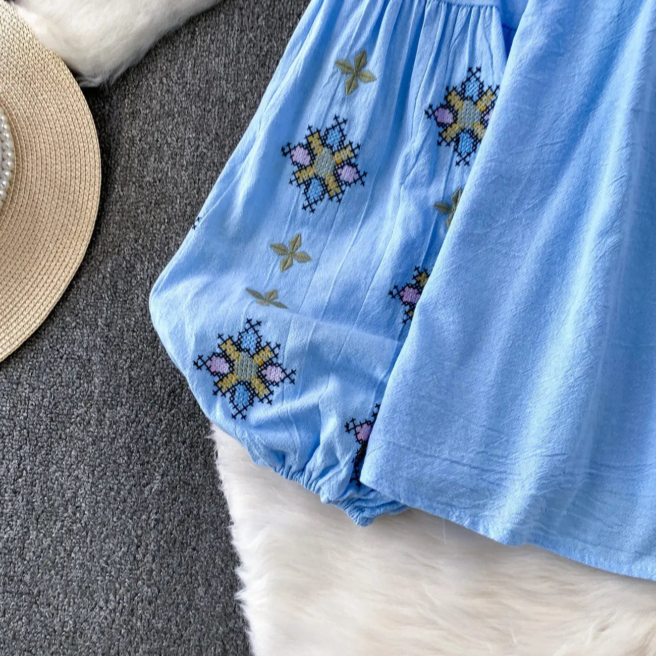 Light blue cotton embroidered lantern sleeve tie neck blouse featuring colorful cross-stitched star and butterfly patterns.