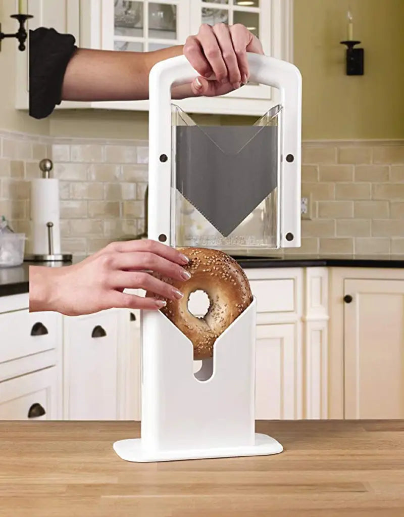 White plastic bagel slicer guillotine with a clear acrylic cutting window black circular accents and safety guard blade.