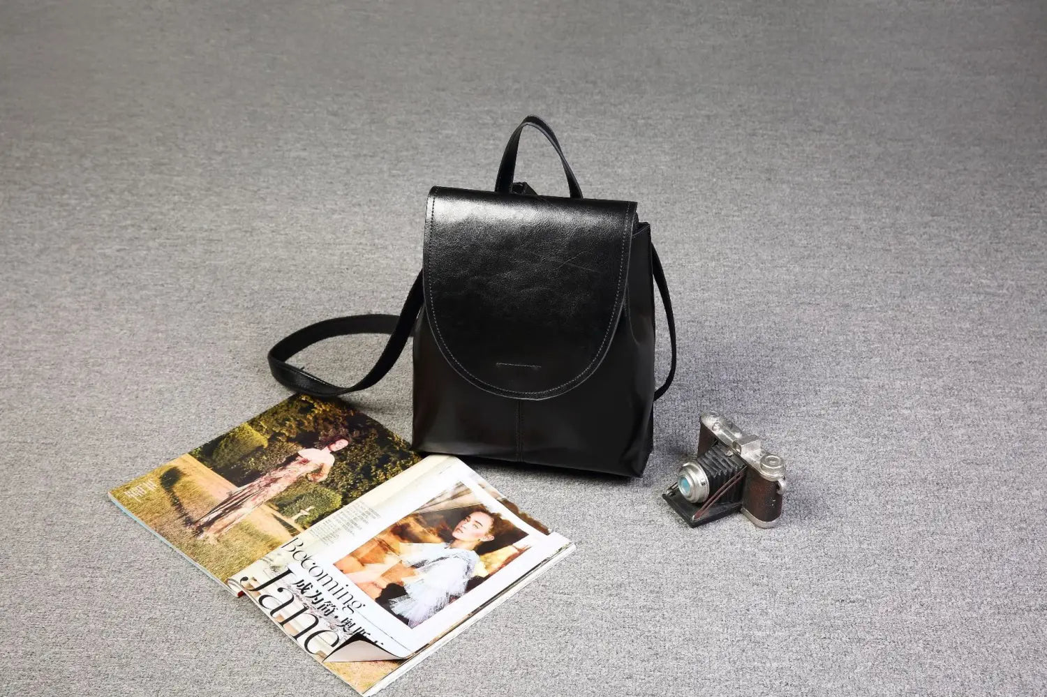 Mochila bandolera de cuero negro con un diseño minimalista y doble correa para uso en moda retro.