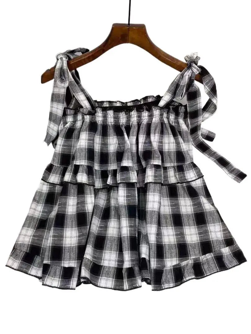 Black and white plaid tiered mini dress with tied shoulder straps ideal for casual or summer wear.