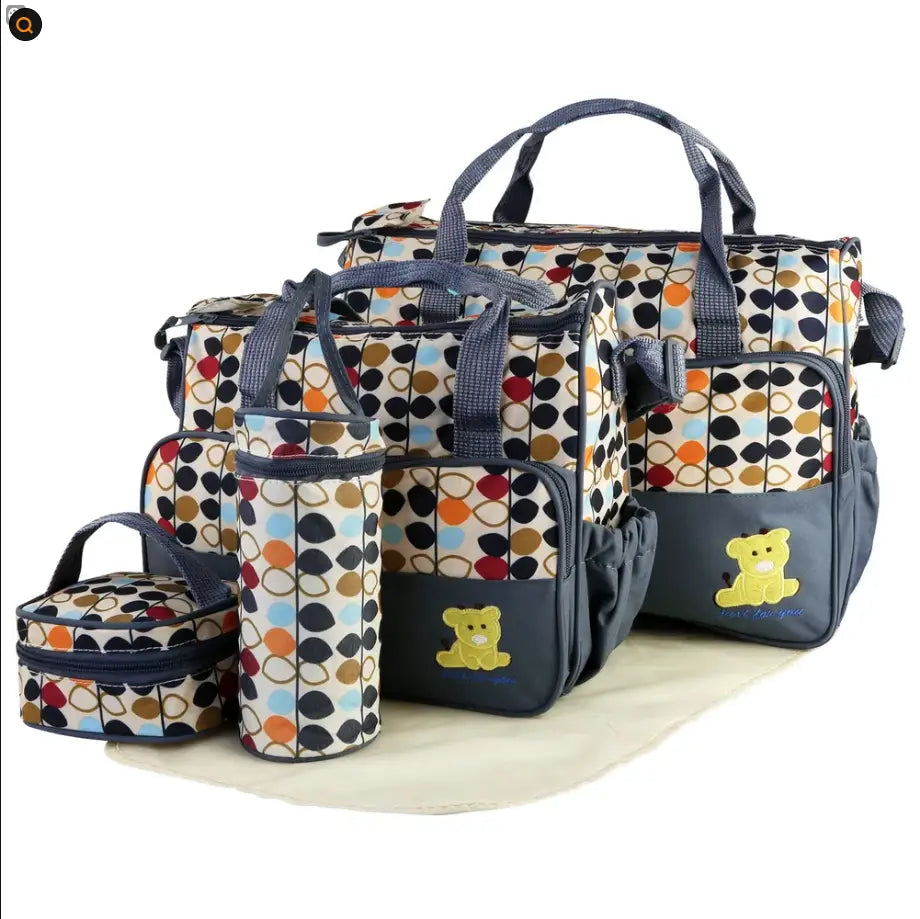 A navy blue and multicolored polka dot 5 piece bear appliqué baby diaper travel bag set featuring a large tote, cylindrical bottle holder, and smaller zippered pouches with embroidered yellow bear appliqués.