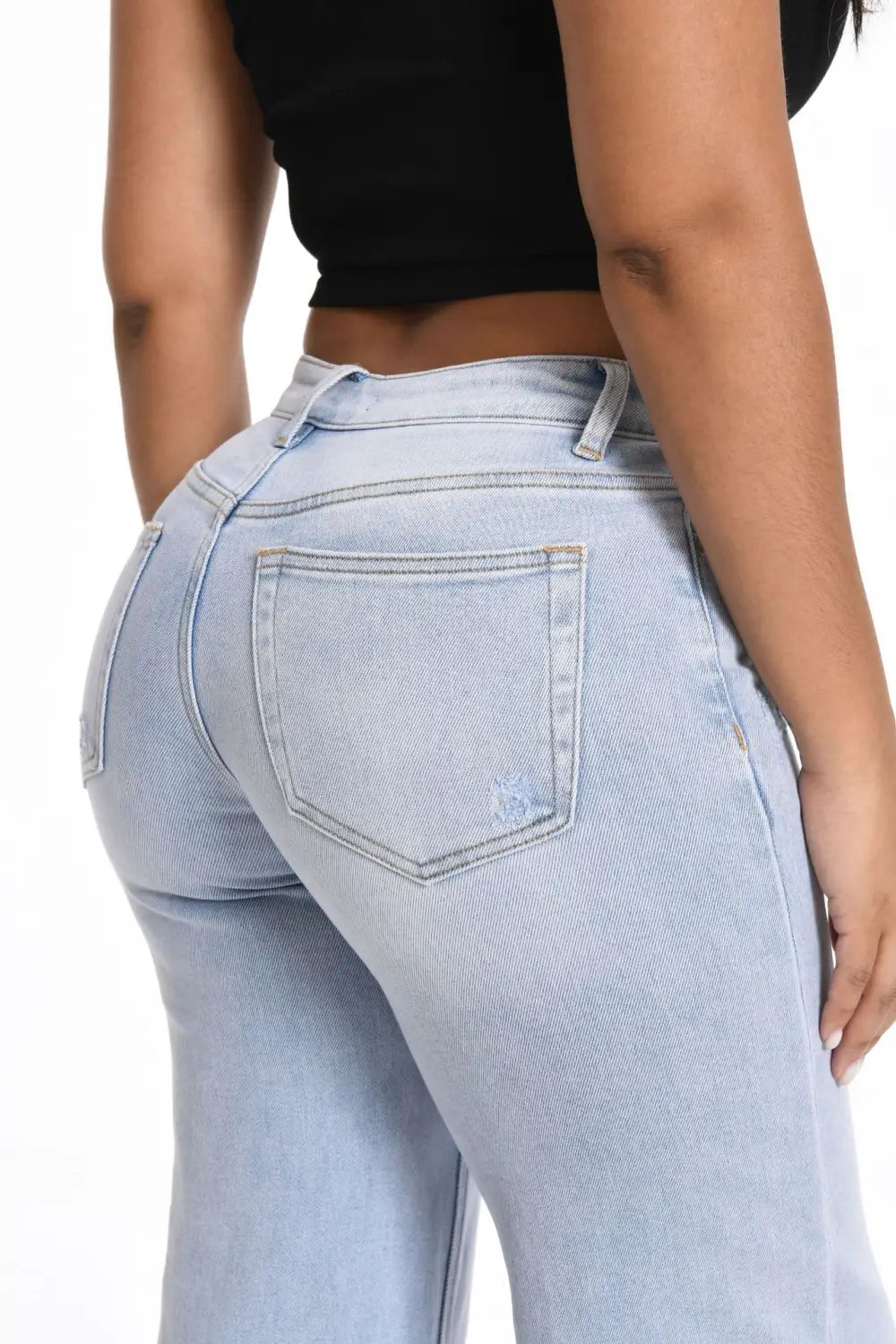 Wide leg stretch denim jeans in light wash with a high rise waist and subtle fading on the back pocket shown from the back side.