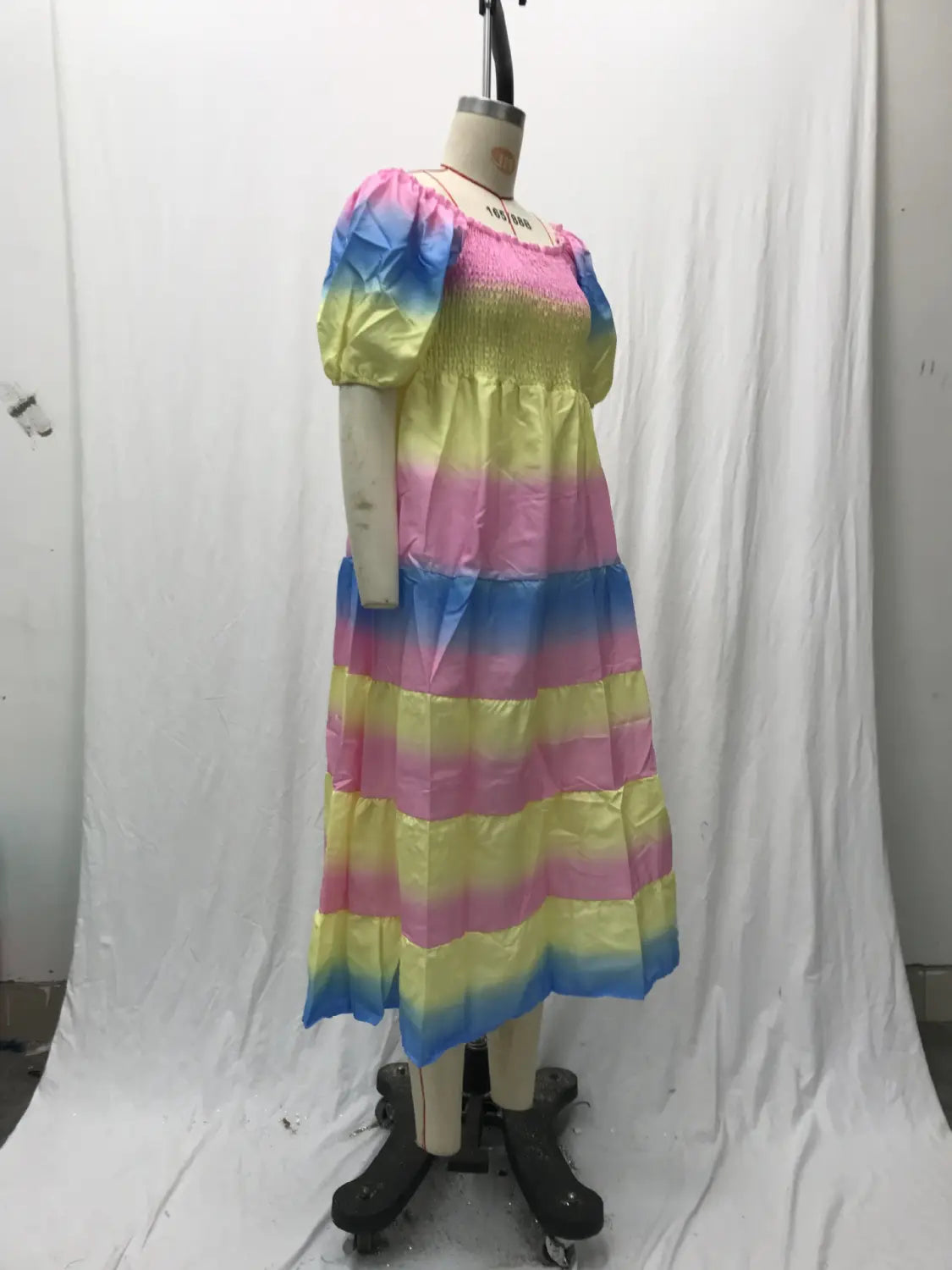 A vibrant rainbow-striped tiered midi dress with floral print smocked bodice, square neckline, and puffy sleeves displayed on a mannequin.