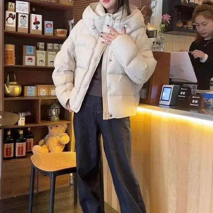 Cremefarbene Pufferjacke mit Kapuze und Knopfverschlüssen, ausgelegt für die Kollektion der Damen-Winterjacke mit lila Steppung und Daunen.