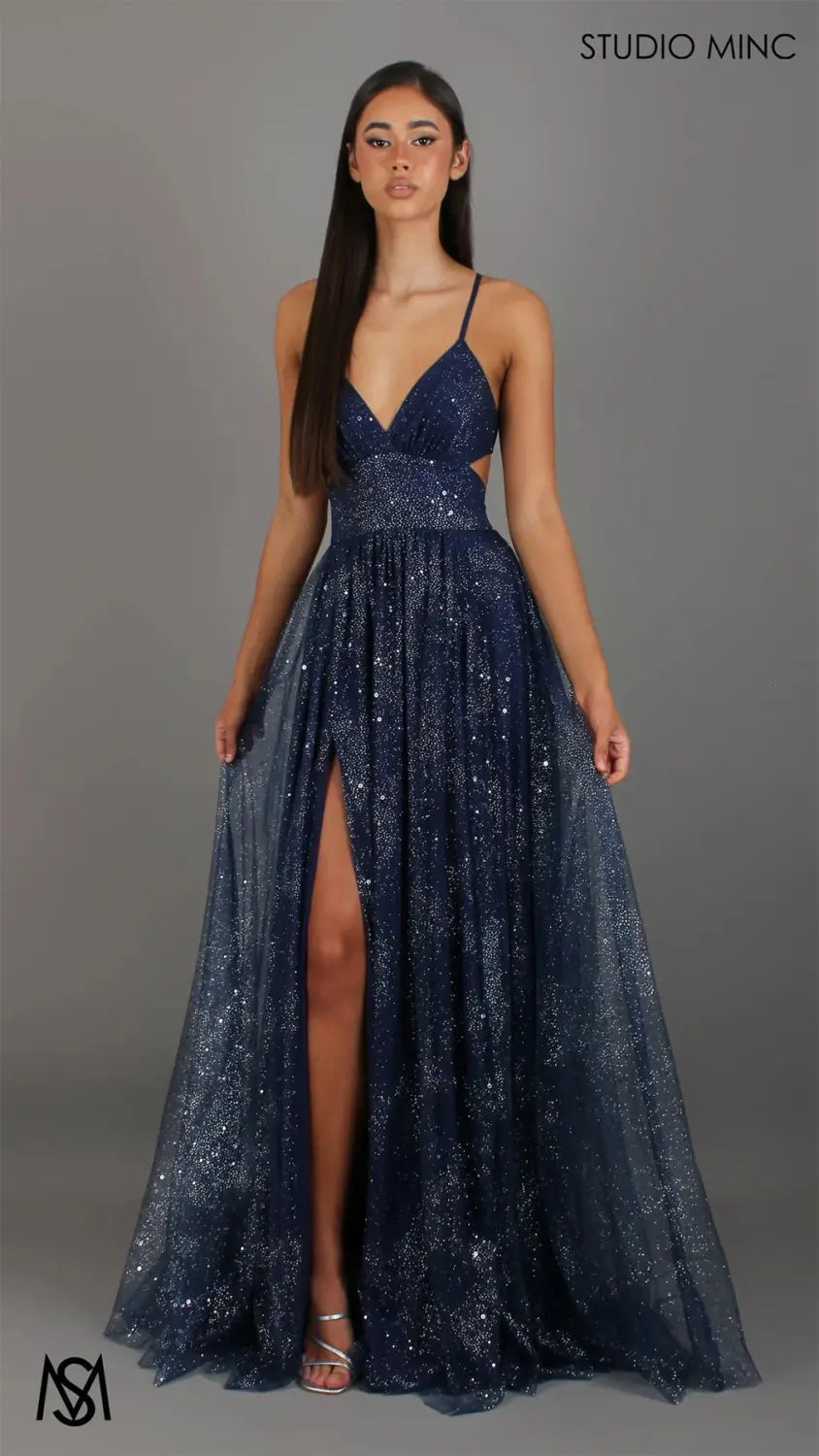 A navy blue sequined evening gown with a plunging v Neckline, high slit, and delicate spaghetti straps, suitable for formal occasions.