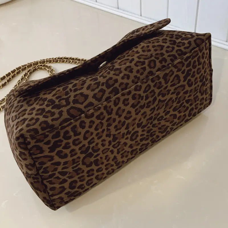 Brown leopard print crossbody bag featuring a gold chain strap.