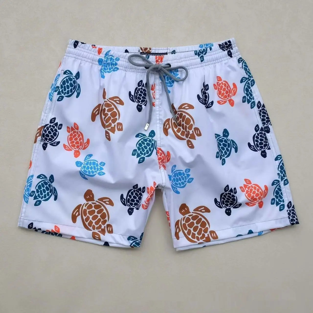 white quick drying beach pants featuring a playful pattern of brown blue and orange sea turtles.
