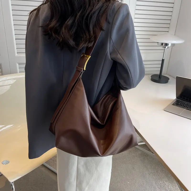 Brown leather shoulder bag with a gold-tone buckle and adjustable strap for elegant daily use