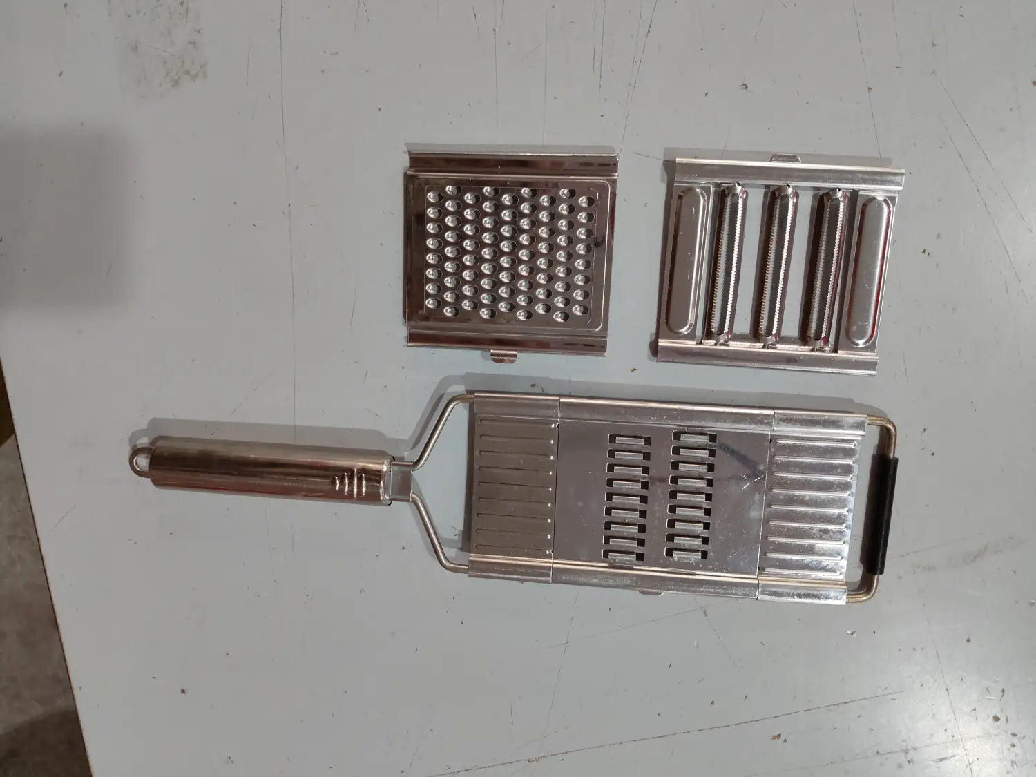 Juego de rallador y cortador multiusos de acero inoxidable plateado con cuchillas intercambiables para una preparación versátil de verduras.