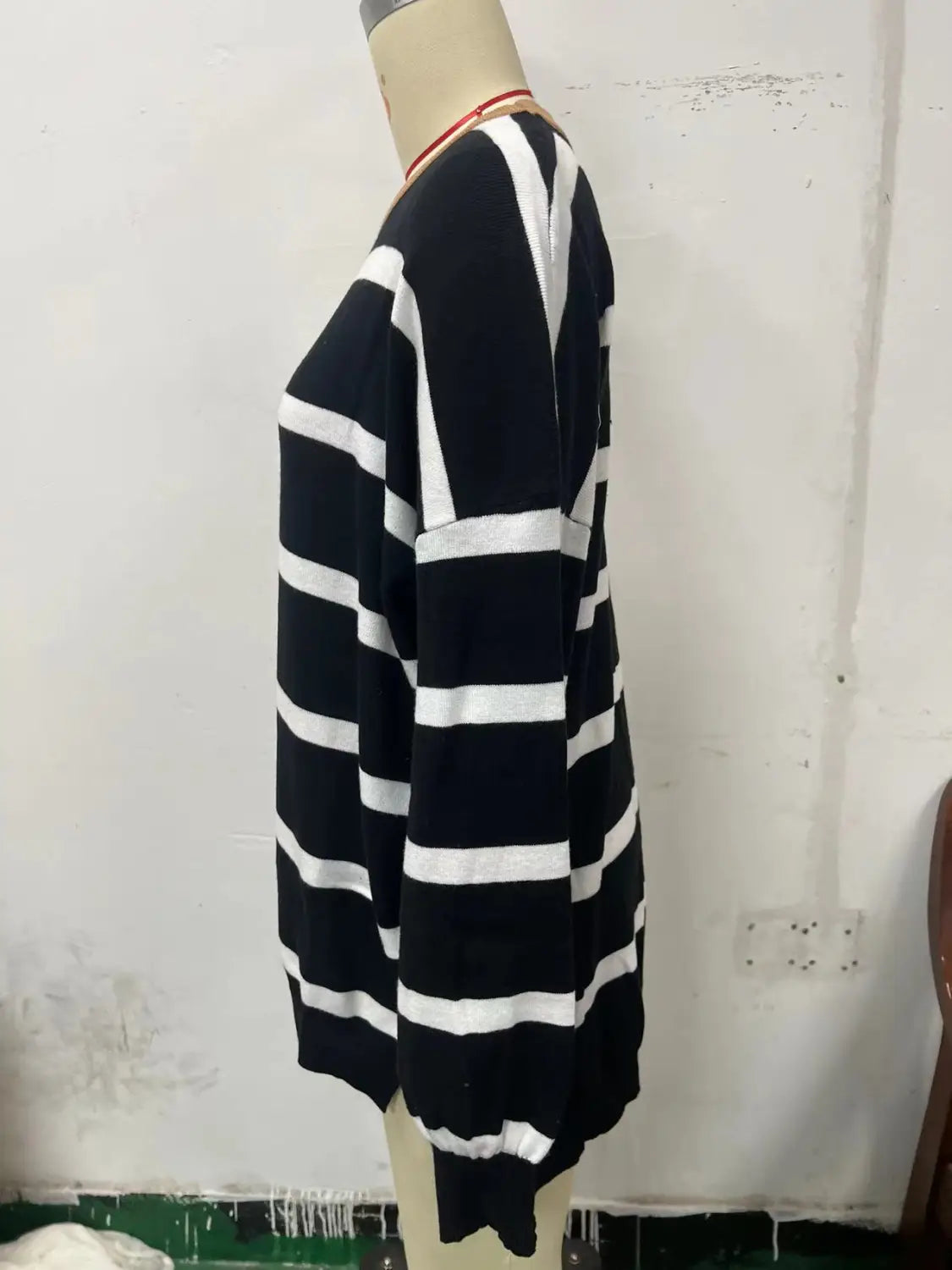 Women’s oversized split color striped knit sweater in black and white with long sleeves displayed on a mannequin.