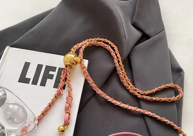 Pink and gold twisted chain strap with golden spherical clasp on a quilted diamond chain crossbody bag with PU leather.