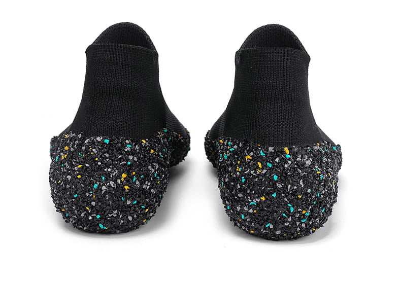 Chaussures de natation et de randonnée à cinq doigts sans chaussures noires dotées d’une adhérence pour chaussettes, avec une semelle texturée brillante à effet pailleté présentant des touches turquoise et jaunes.