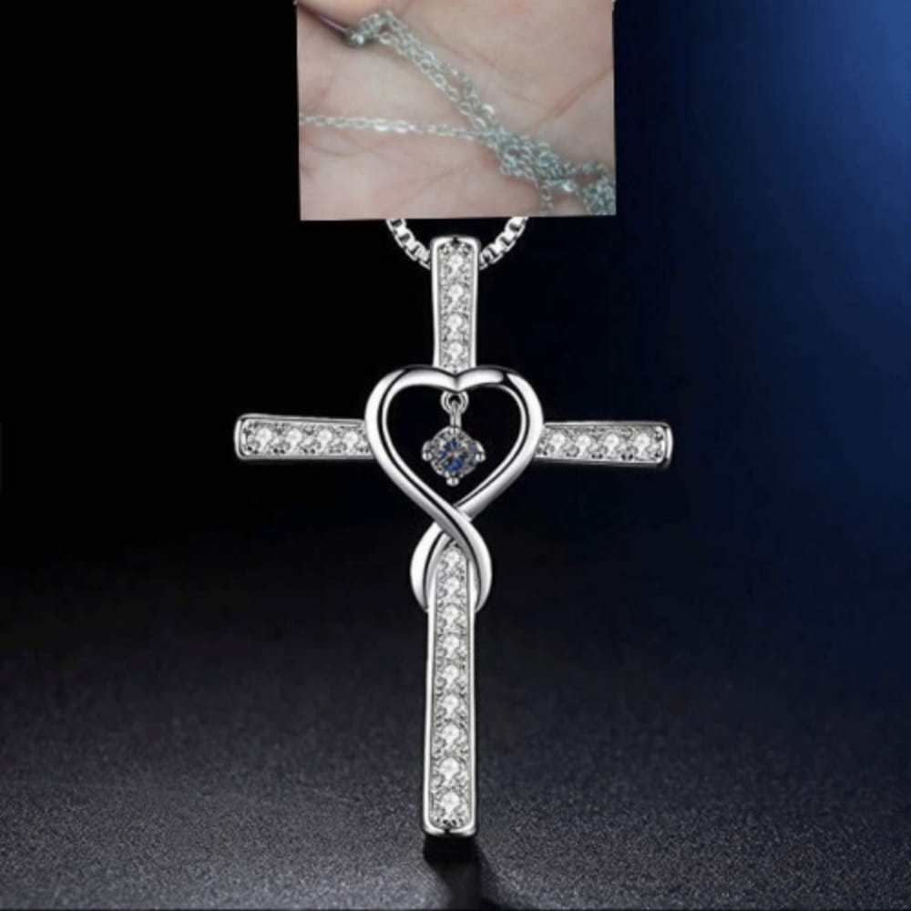 Silver cross pendant necklace featuring a heart-shaped center with embedded clear crystals and an infinity knot design in a birthstone crystal necklace style.
