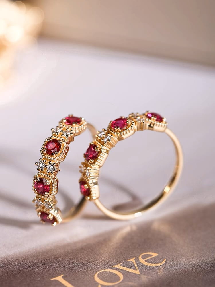 Elegant 18k gold plated band ring featuring vibrant pigeon blood rubies and sparkling diamonds set in an intricate textured design.
