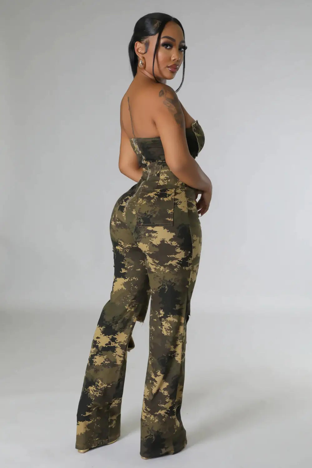 Eine Frau in Übergröße trägt einen Camouflage-Aussteller-Jeansjumpsuit mit hochtaillierten Hosen und einem trägerlosen Oberteil