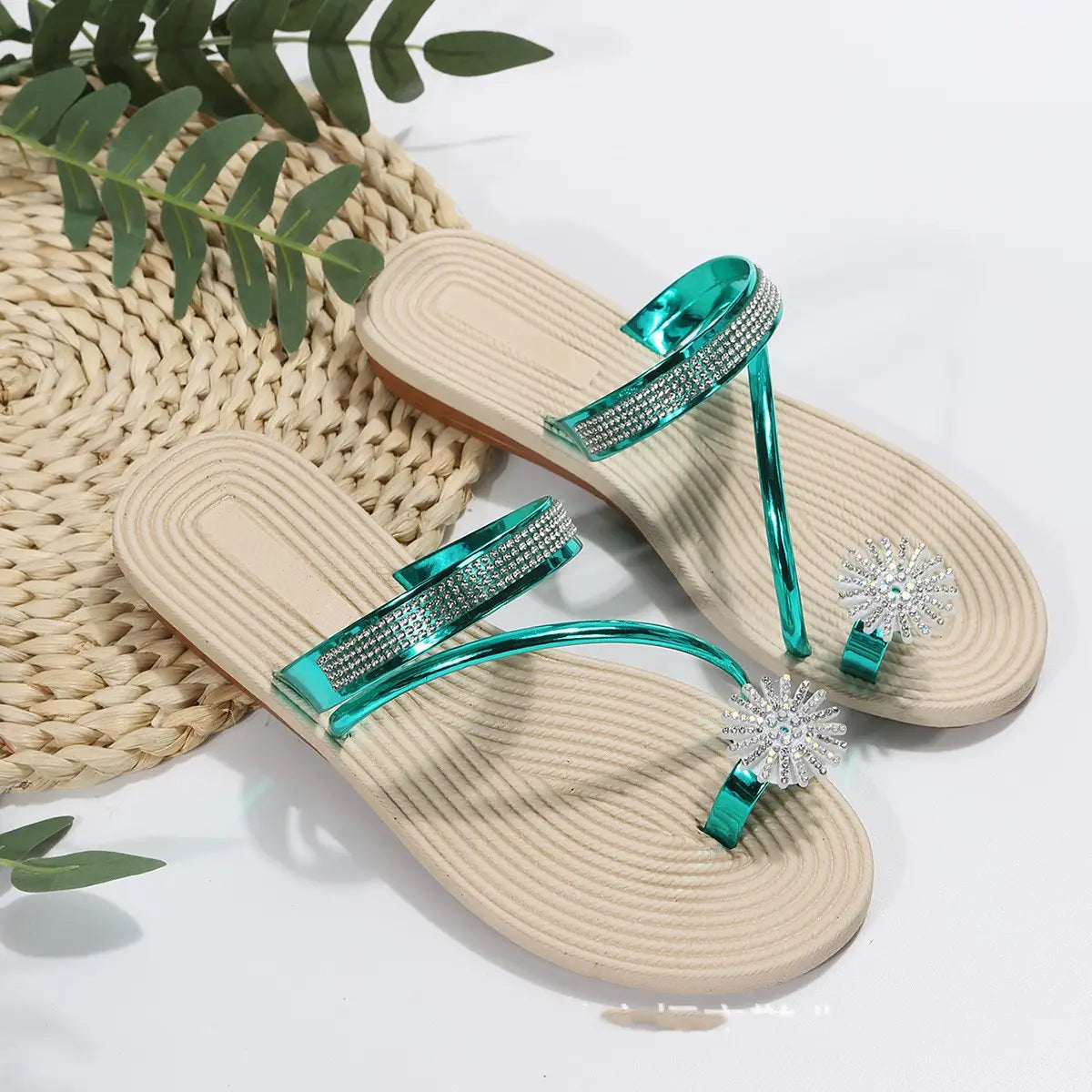 Sandalias de verano con tiras y pedrería para tallas grandes con diseño tipo tanga metálico color verde azulado, con tiras adornadas con pedrería y postes con forma de flor en la punta.