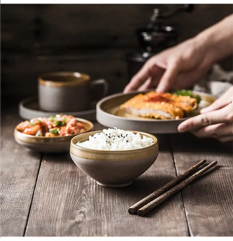 A rustic gray ceramic bowl with a subtle golden rim filled with white rice and topped with black sesame seeds from a ceramic tableware set retro Japanese dinnerware.