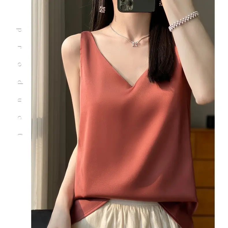 A soft rust-colored silky satin v-neck camisole top with a sleeveless design.
