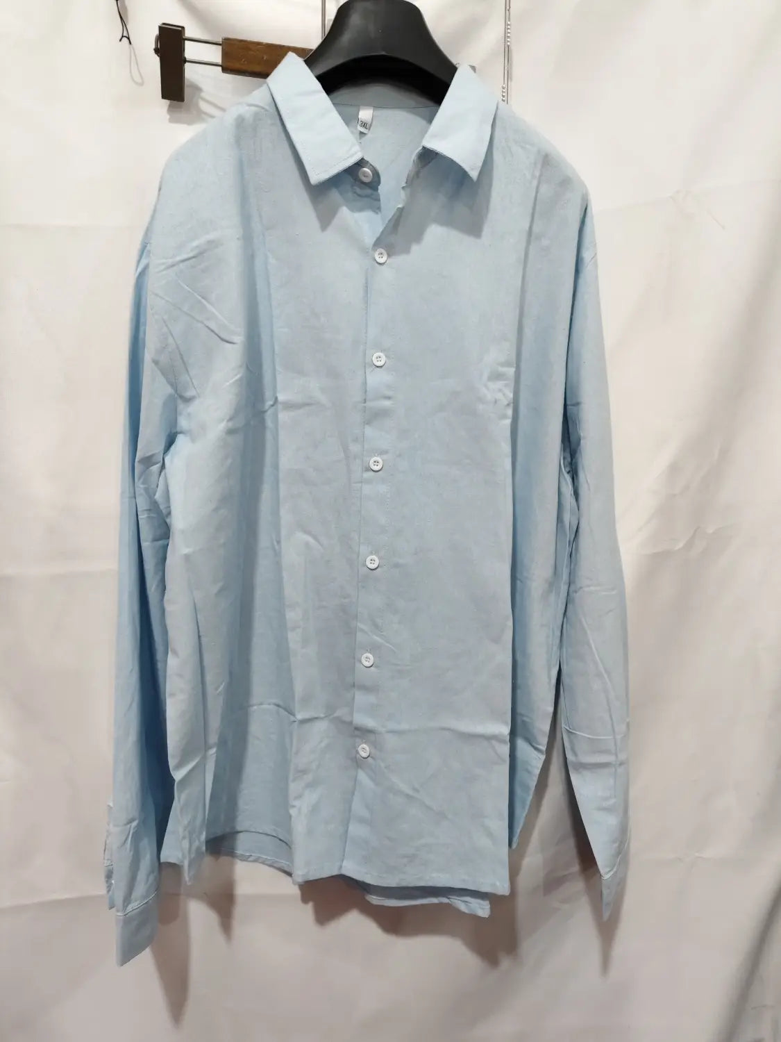 Men linen casual button down shirt in light blue featuring long sleeves white buttons and a classic collar.