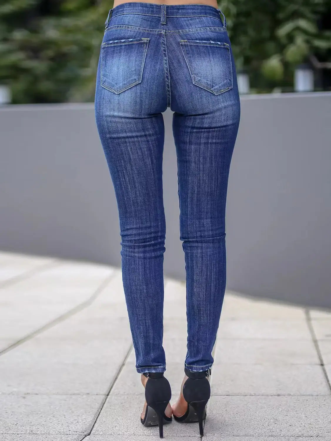 women’s high-waisted stretch skinny jeans in blue denim with a slim fit featuring classic back pockets shown from the back side