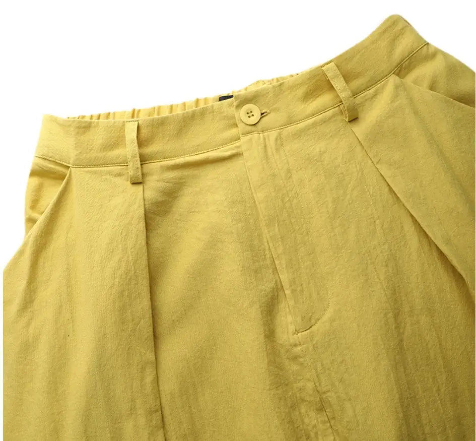 Pantalon en lin jaune avec taille boutonnée et plis, présenté aux côtés d'une jupe longue maxi en satin taille haute au tombé fluide.