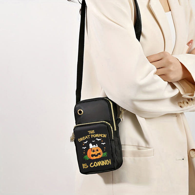 Black crossbody phone bag with embroidered Halloween design featuring a smiling pumpkin, bats, and gold lettering saying the great pumpkin is coming, suitable for festive use.