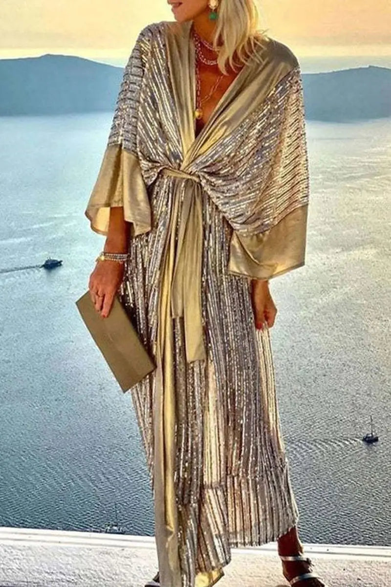 A shimmering gold sequined metallic bat sleeve pleated maxi dress with a draped flowing design and wide bell sleeves.