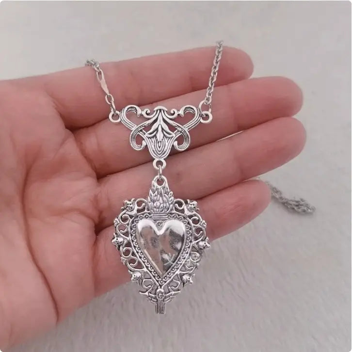 Vintage silver filigree heart pendant necklace with ornate detailing red enamel center and silver chain.