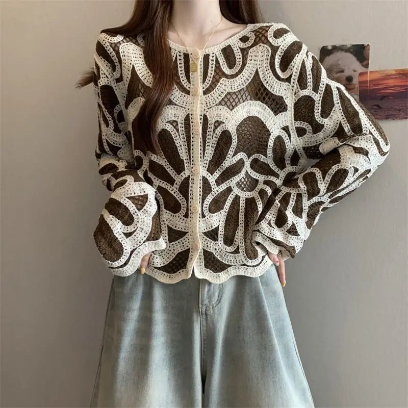 Ein cremefarbenes, kunstvoll gehäkeltes Cardigan mit Blumenmuster über einer dunkelbraunen Mesh-Basis in der Stilrichtung eines lockeren Pulloveroberteils.