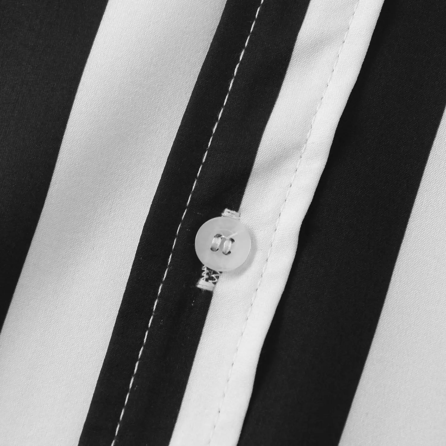Un bouton rond transparent, avec un léger éclat, sur une chemise pour homme à rayures, à manches courtes, boutonnée sur le devant, arborant des rayures verticales noir et blanc marquées, sur un tissu lisse