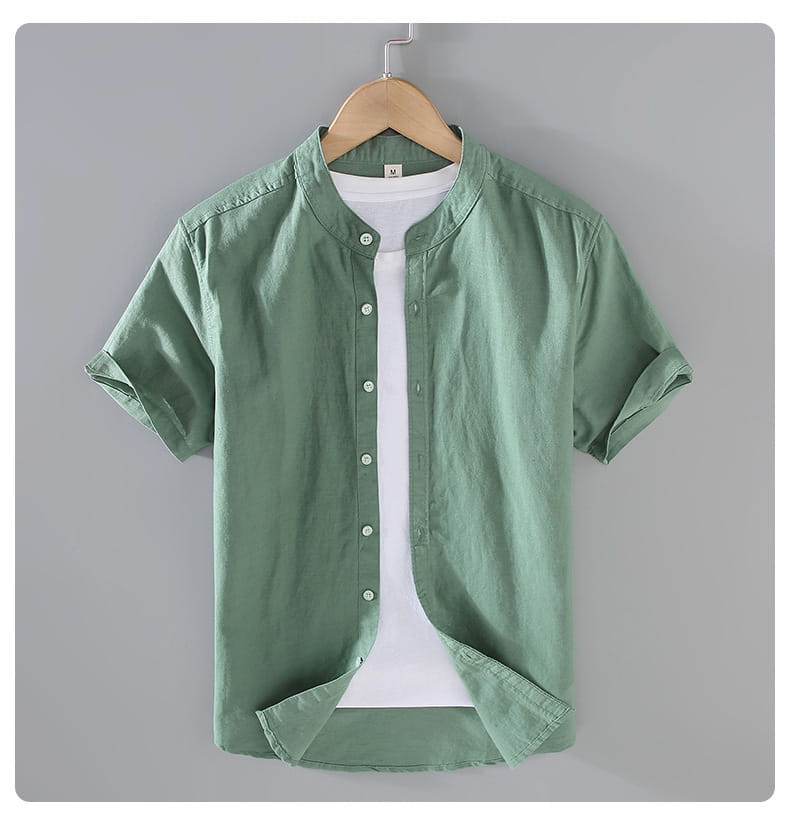 A light green men linen short sleeve shirt with a mandarin collar and rolled cuffs hanging on a wooden hanger.