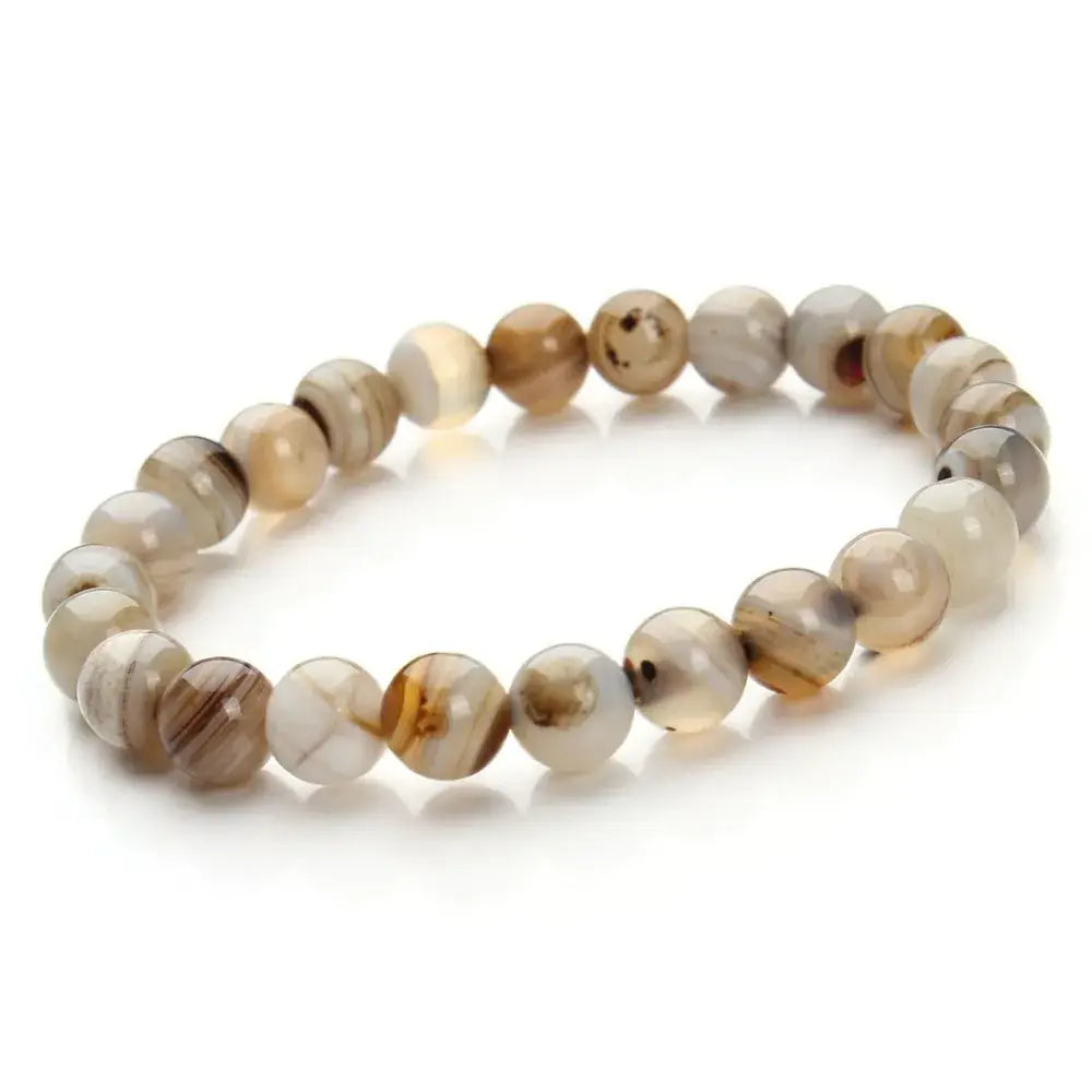A delicate stretchy bracelet composed of smooth round agate beads in natural earth tones with swirling patterns in the natural polished gemstone and agate beaded bracelet collection.