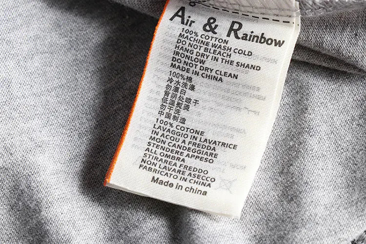 Etiqueta de cuidado de la tela blanca con borde naranja que muestra la marca Air y Rainbow e incluye instrucciones de lavado multilingües en la camiseta tipo jersey de color liso lavado de manga larga.