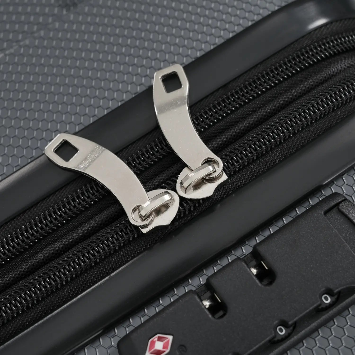 silver-toned zipper pulls with a sleek metallic finish and looped design are attached to black zippers on a textured gray 24 inch expandable hardshell checked luggage with tsa lock.
