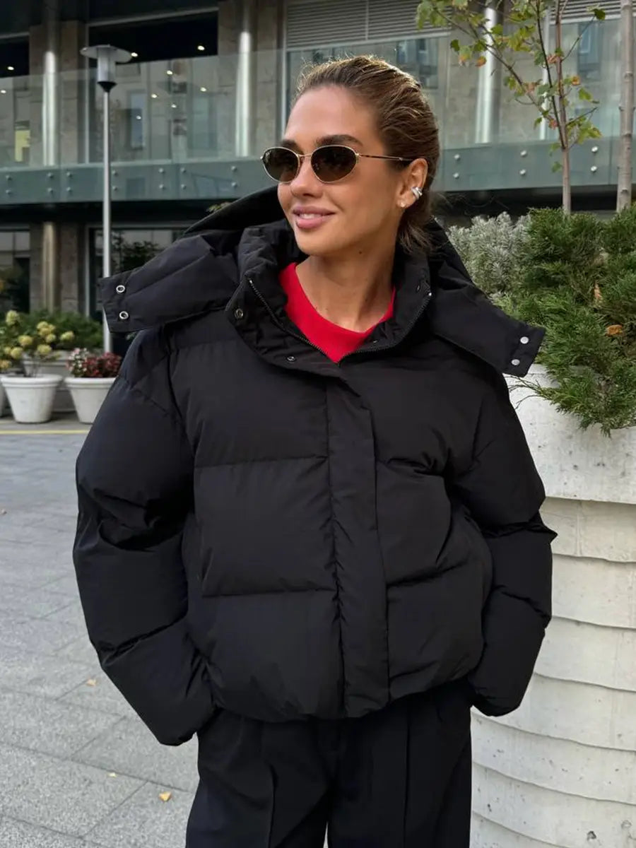 Schwarze wattierte Pufferjacke mit Kapuze mit warmem, isolierendem Design, ideal für das Tragen bei kaltem Wetter.
