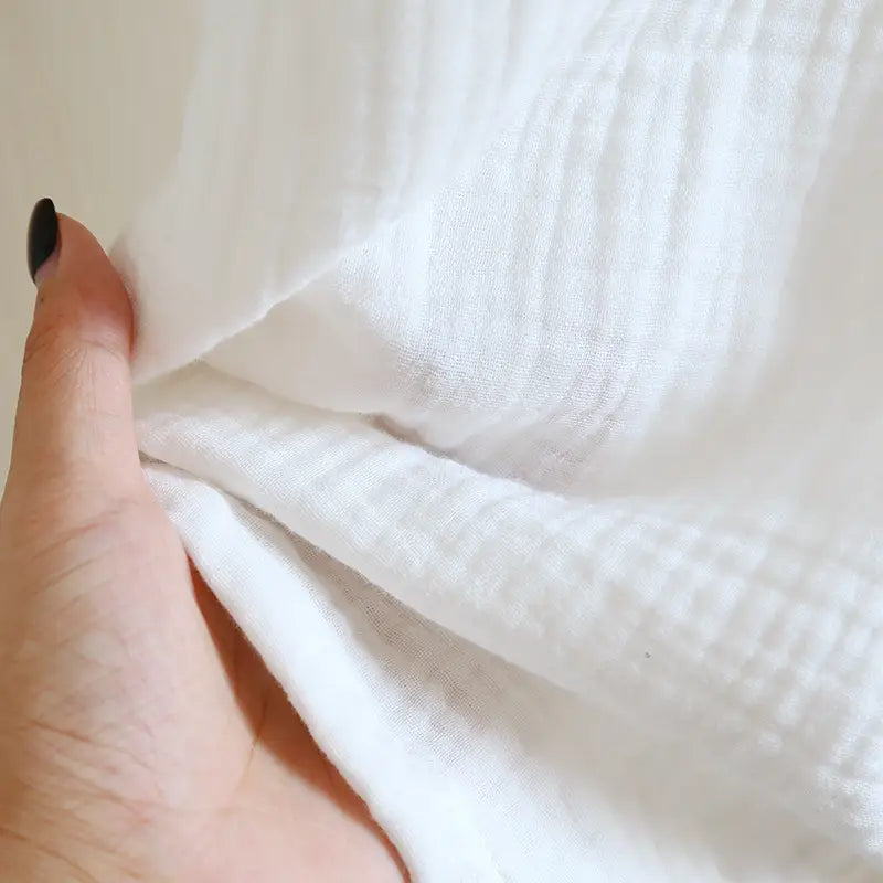 Tissu en mousseline de coton blanc avec un tissage texturé souple, mis en avant dans un peignoir en gaze de coton pour homme