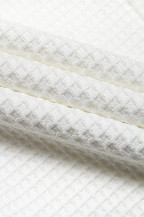 white waffle-weave fabric with a textured diamond-patterned surface on men’s slim fit waffle knit straight leg business trousers