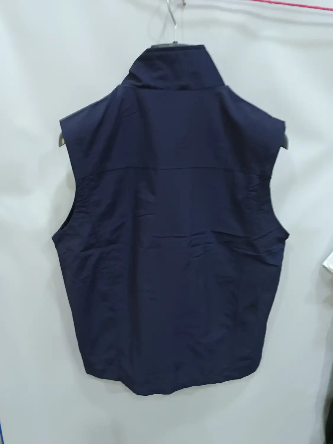 Chaleco utilitario impermeable sin mangas de color azul marino oscuro con cuello alto y dos bolsillos frontales para múltiples opciones de almacenamiento.