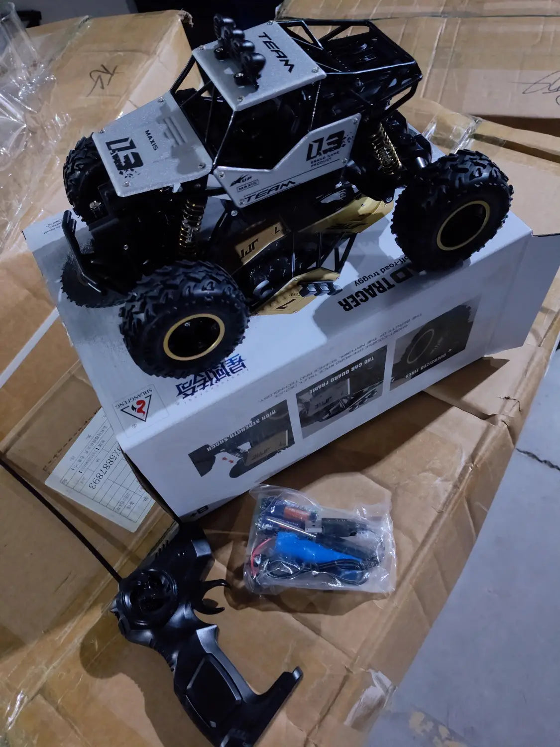 Camion teledirigido RC todoterreno 4WD de alta velocidad en negro y blanco, tipo crawler, con neumáticos resistentes, suspensión con detalles dorados y branding del equipo en el chasis.