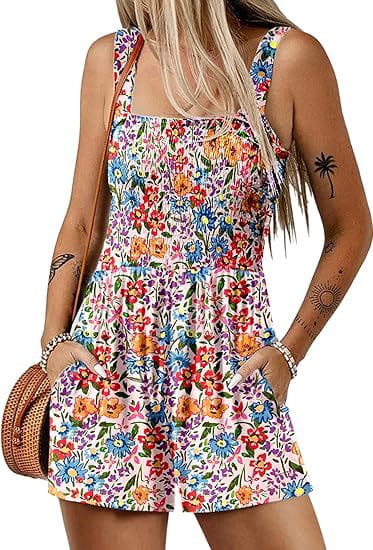 Mono tipo peto vibrante con estampado floral sin mangas para playa de verano, con tirantes finos y bolsillos laterales, confeccionado con tejido ligero y con colores vivos, incluidos rojo, azul, amarillo y morado sobre un fondo claro.