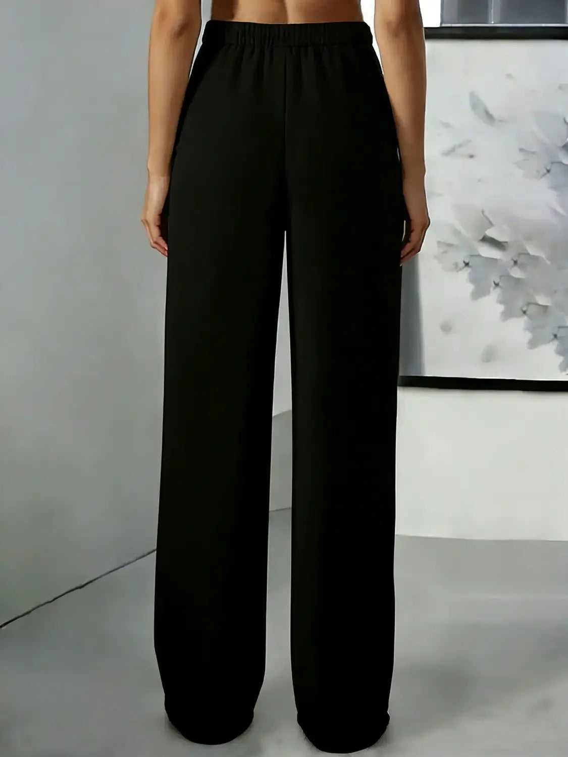 Pantalons noirs à jambes larges avec une ceinture élastique à la taille haute et un tissu lisse et fluide, conçus pour un look confortable et élégant