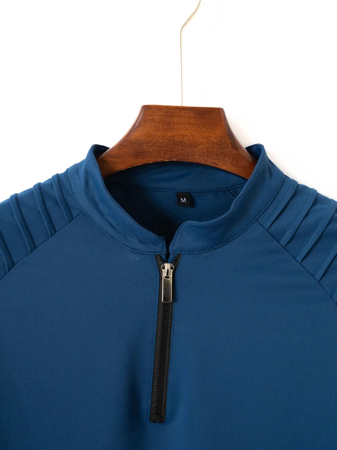 Herren-Quarter-Zip-Athletik-Poloshirt in Blau mit schwarzem Reißverschluss und gerippten Schulterdetails, entworfen für aktive Kleidung.